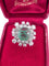 Bague 55 Magnifique bague en or blanc avec une émeraude centrale et des diamants tout autour. 58 Facettes