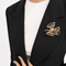 Broche Broche nœud stylisé en or jaune 18 carats, diamants et émeraudes 58 Facettes 36314